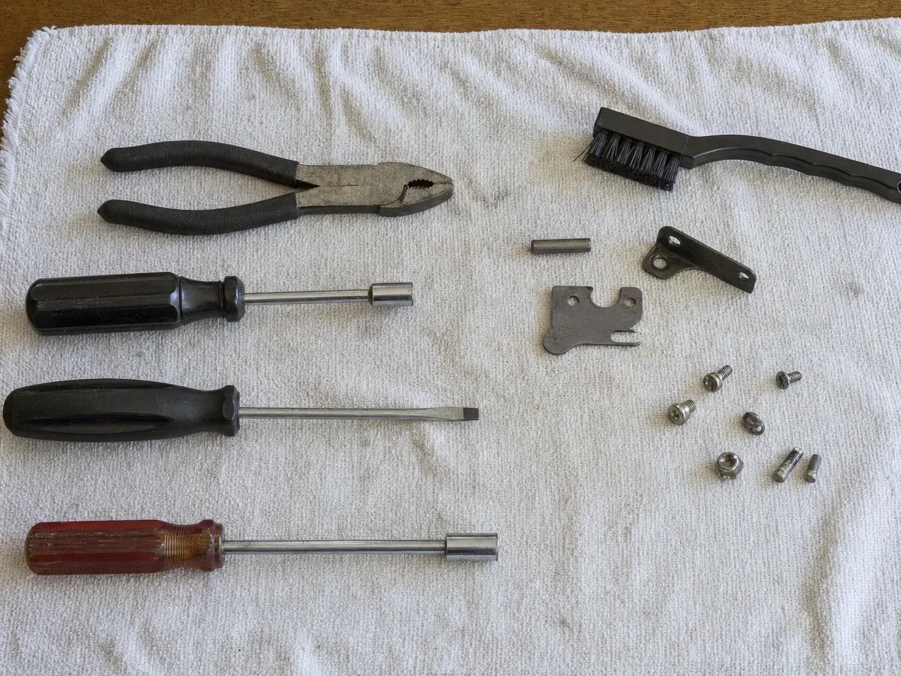Black brush, pliers, screwdrivers, small screws and brackets on cloth