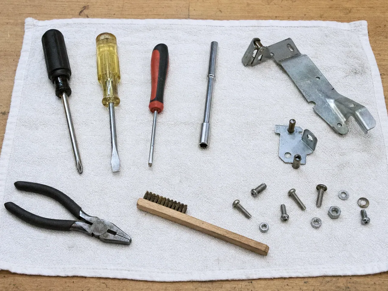Hinge bracket, screws, nut driver, screwdrivers, brush and pliers