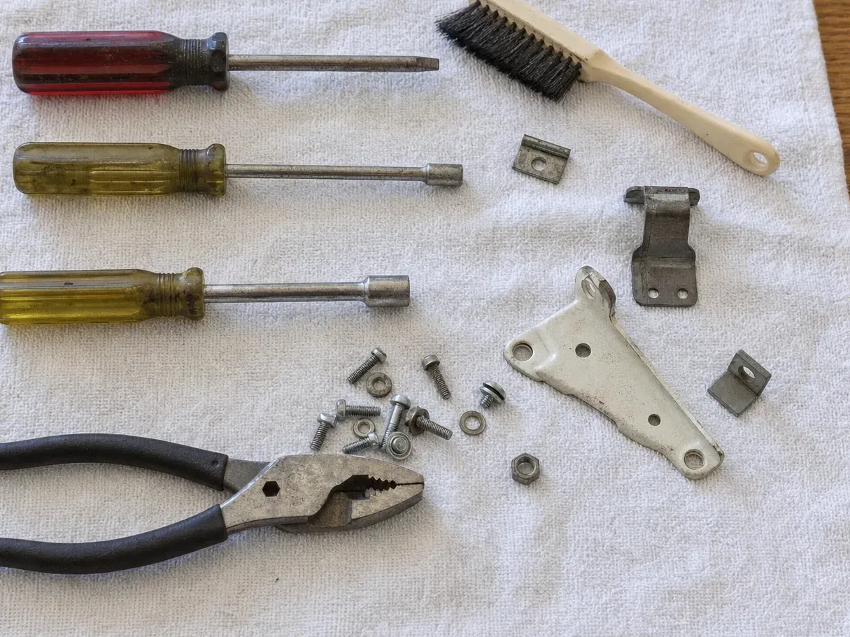Brackets, screws, nut drivers and slip-joint pliers on a towel