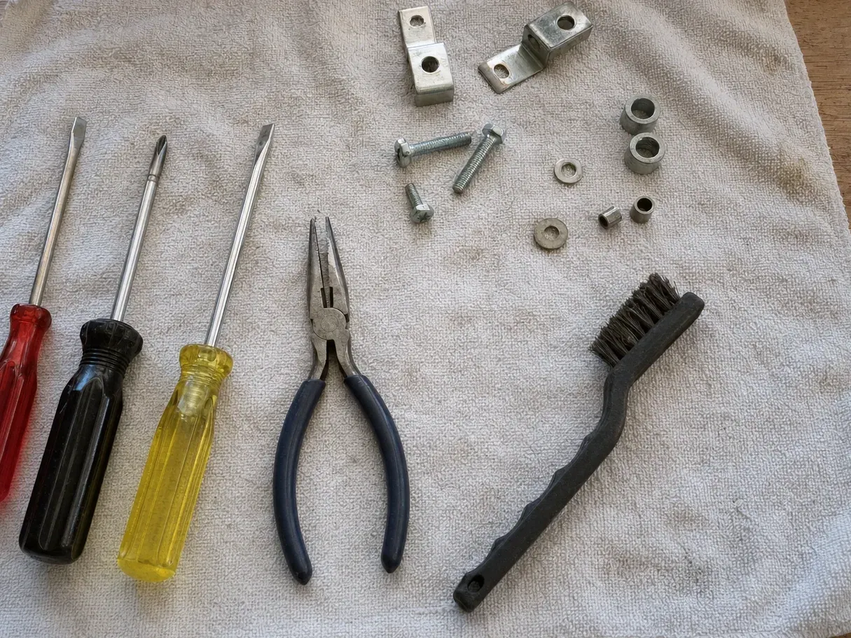 Brackets, spacers, bolts, pliers and three screwdrivers on towel