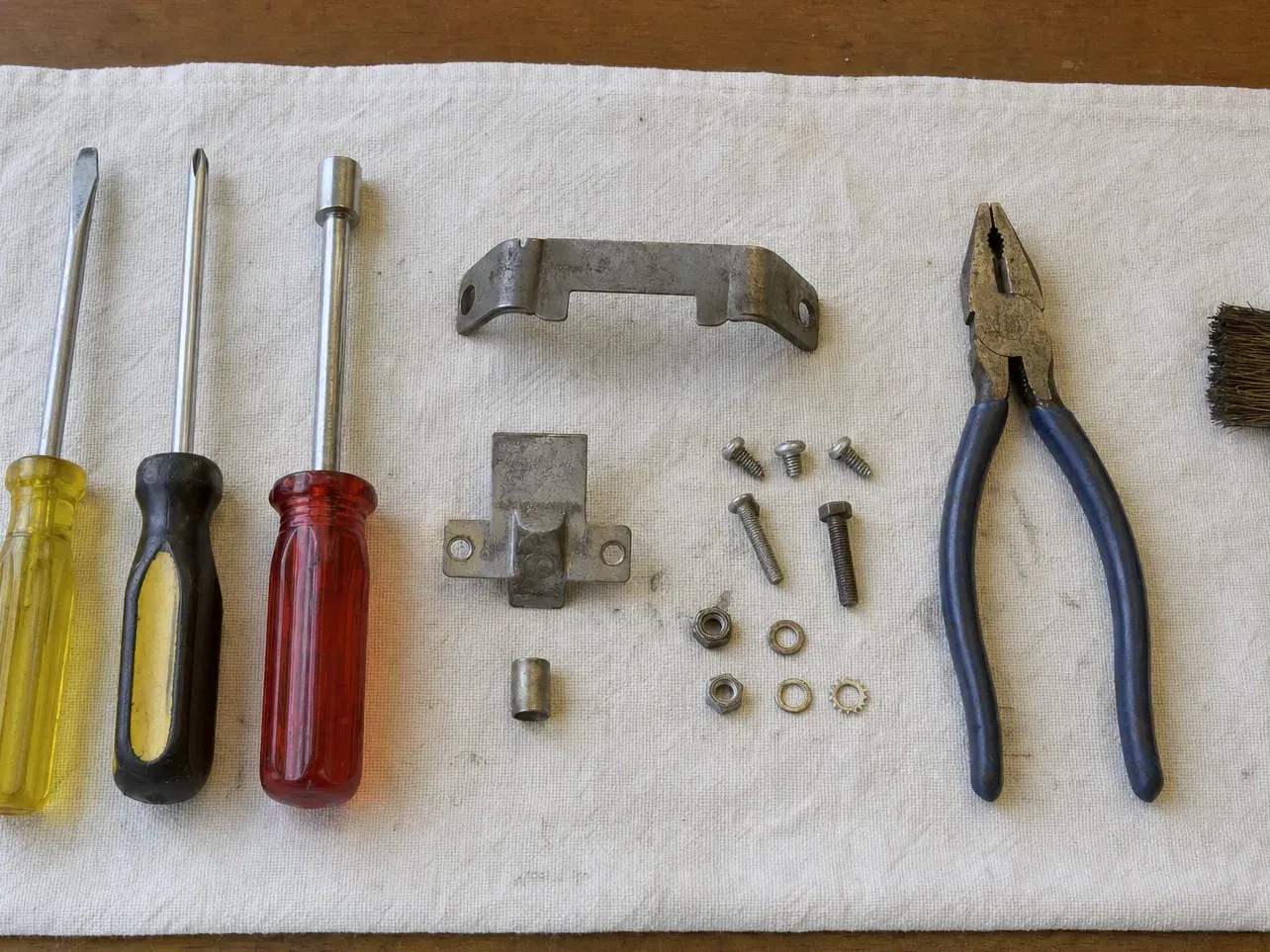 Curved bracket, catch plate and screws with pliers and screwdrivers
