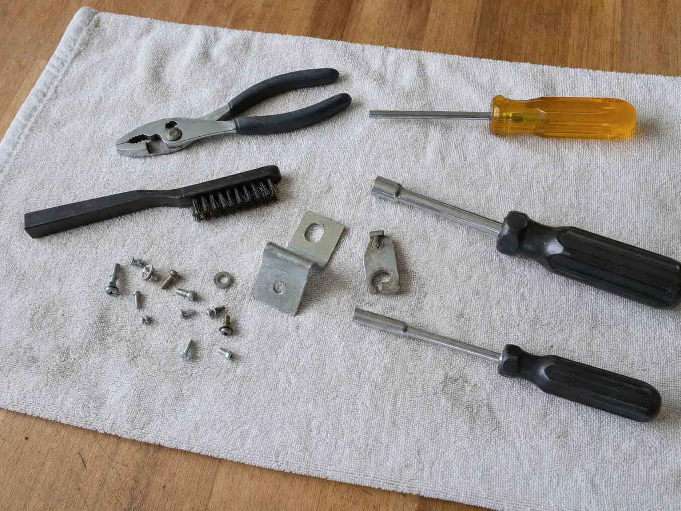 Nut drivers, pliers, brush, brackets and screws on folded towel