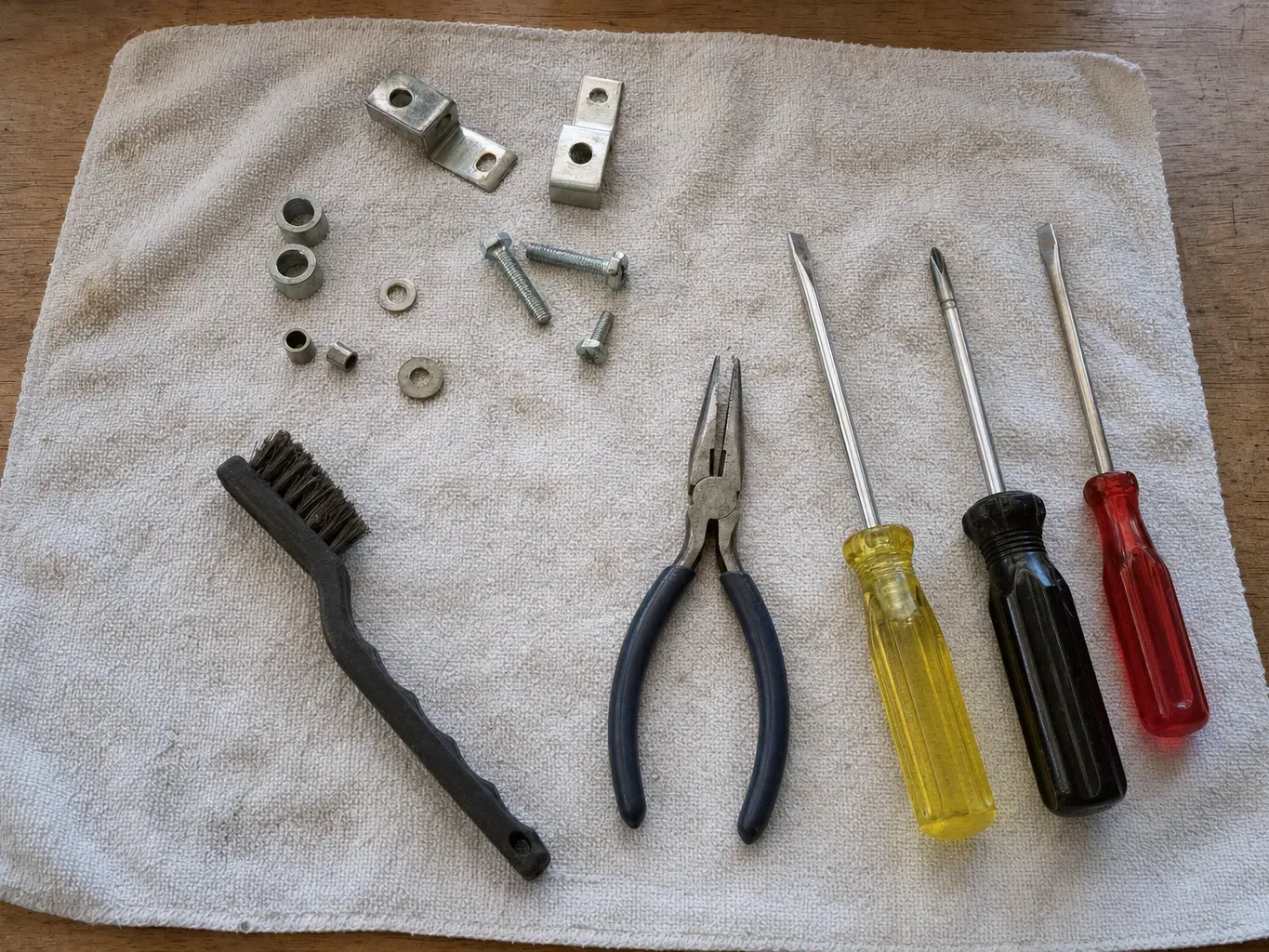 Screwdrivers, needle-nose pliers, brush, bolts and spacers on towel